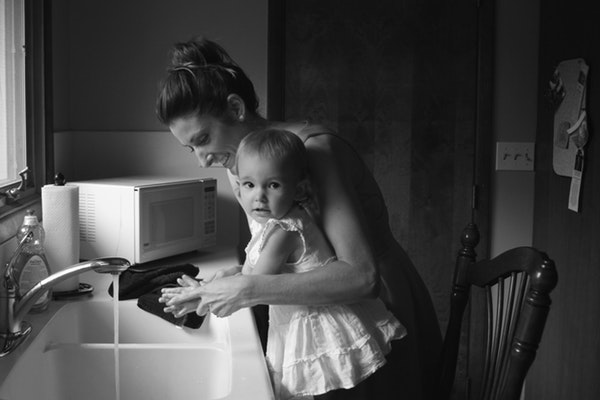 mom helping her daughter wash her hands at the kitchen sink
