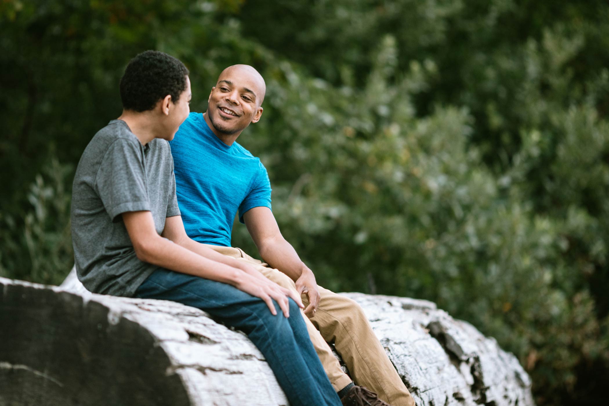 iStock-1270105485-web father and son sitting on a log talking