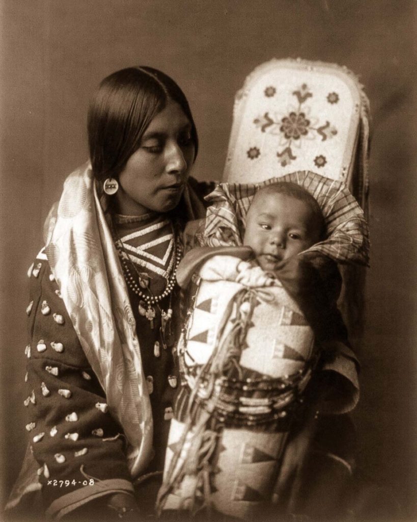 A Native American woman from the Apsaroke tribe holding her infant.
