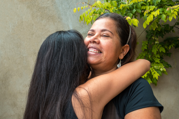 A mom hugging her teenage daughter.