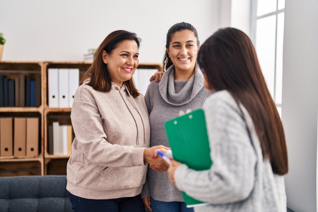 Three woman patient and psychologist shake hands at psychology center