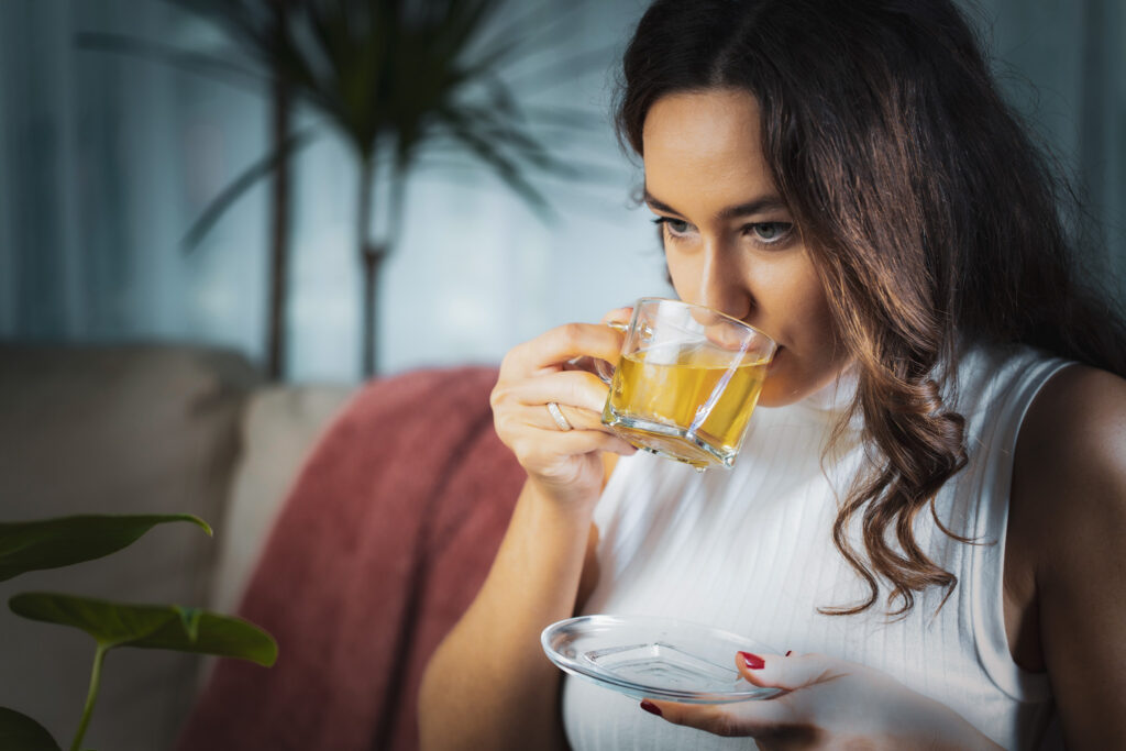 Beautiful young woman drinking hot kratom tea in living room