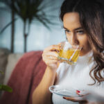 Beautiful young woman drinking hot kratom tea in living room
