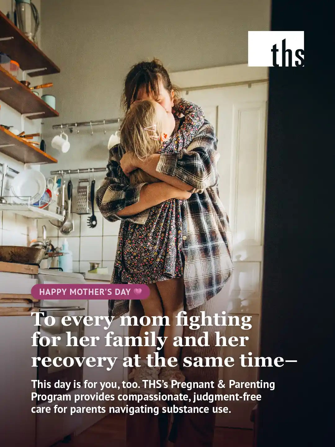 A Mother's Day graphic for Therapeutic Health Services. The THS logo appears in the top right on a dark background. A candid photograph fills the frame showing a woman in a plaid flannel shirt embracing a young child in a floral dress in a warmly lit kitchen, their faces hidden as they hold each other close. Kitchen shelves with mugs and utensils are visible in the background. A dark gradient fades up from the bottom of the image. A pink pill-shaped badge reads "Happy Mother's Day" with a heart emoji. Below, bold white text reads: "To every mom fighting for her family and her recovery at the same time—" Below in smaller white text: "This day is for you, too. THS's Pregnant & Parenting Program provides compassionate, judgment-free care for parents navigating substance use."