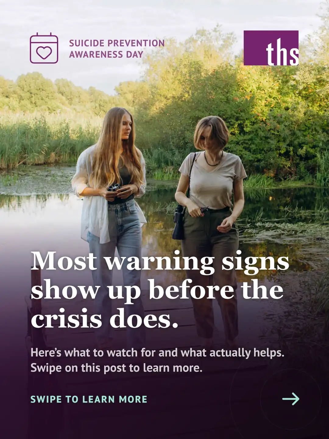 Photo of two women in warm, late-day sunlight, talking as they walk along a wooden dock beside a pond surrounded by greenery. A dark purple gradient overlay covers the lower two-thirds of the image. Top left: a calendar-with-heart icon and the text "SUICIDE PREVENTION AWARENESS DAY." Top right: the THS logo. Bold white headline: "Most warning signs show up before the crisis does." Below it: "Here's what to watch for and what actually helps. Swipe on this post to learn more." Bottom left, in teal: "SWIPE TO LEARN MORE" with a right-pointing arrow.